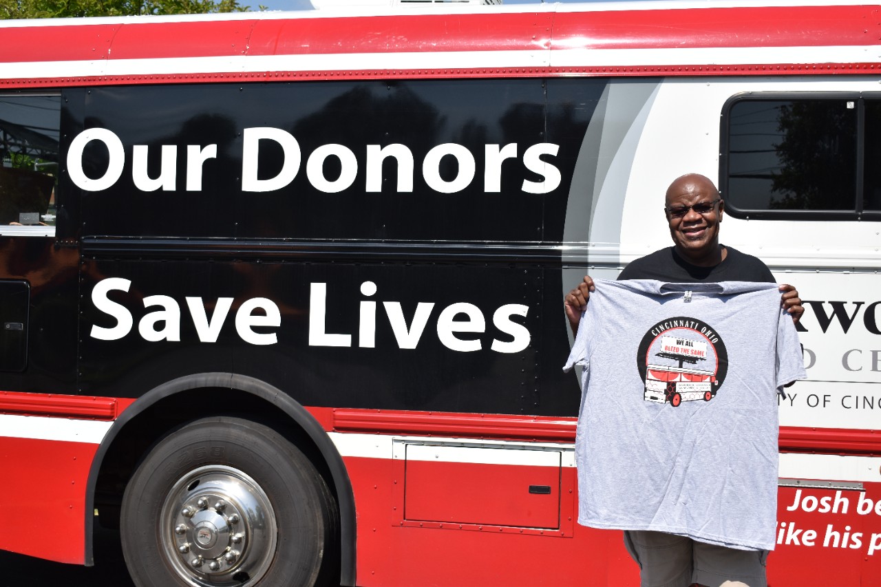 Myron standing next to a Hoxworth bus that reads "Our Donors Save Lives"